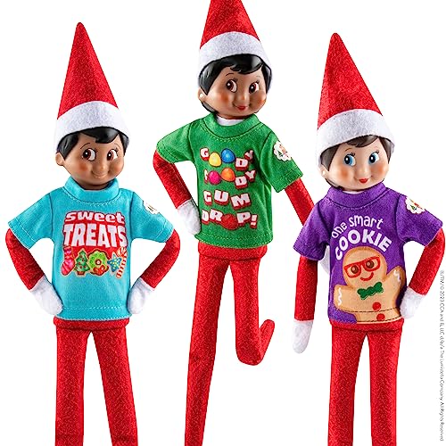 The Elf on the Shelf Sweet Treats Tees Claus Couture - Juego de Ropa para tu Elfo Explorador, los Accesorios Incluyen una Maleta de Lata Coleccionable con un trío de Camisetas de tamaño Elfo